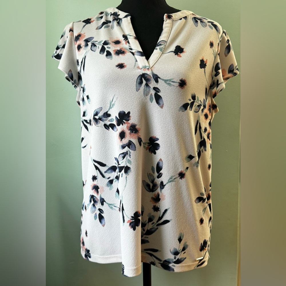 White, blue, and pink Calvin Klein blouse with capped, flowy sleeves.